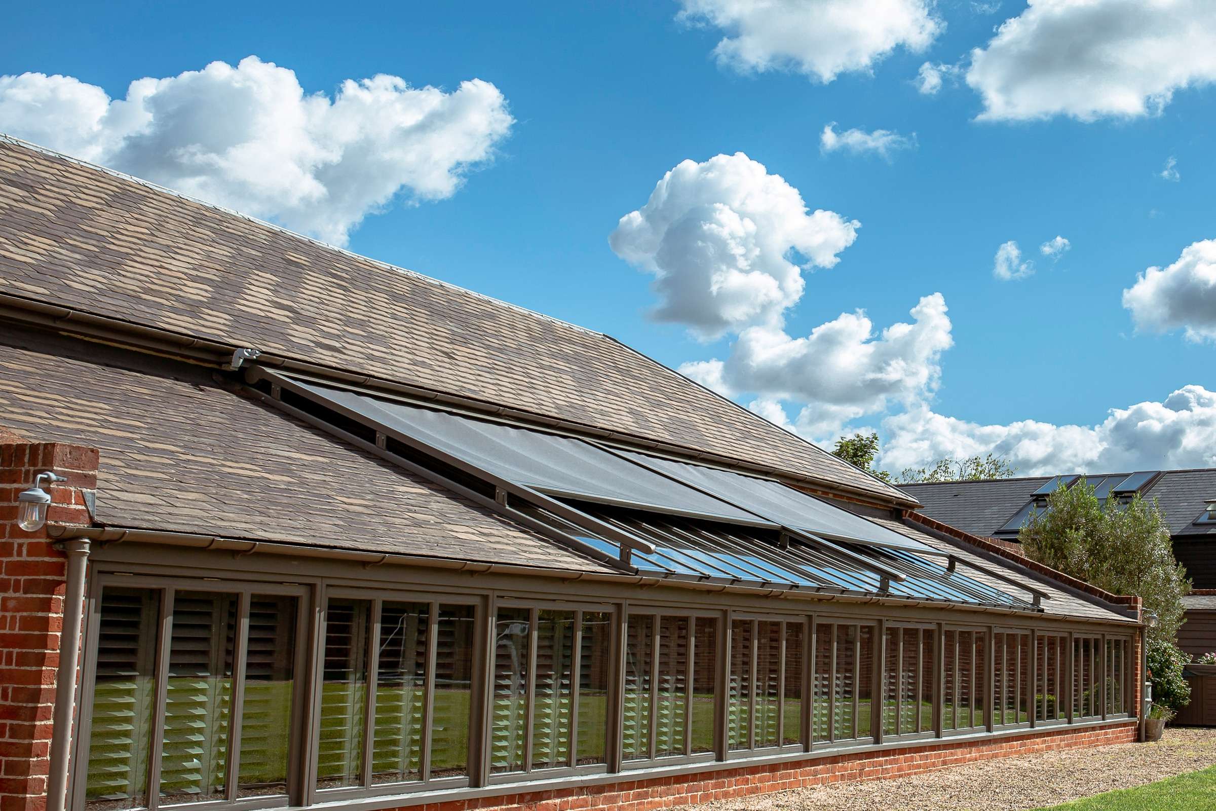 external blinds on a glass roof - bright an blue sky is in the background.